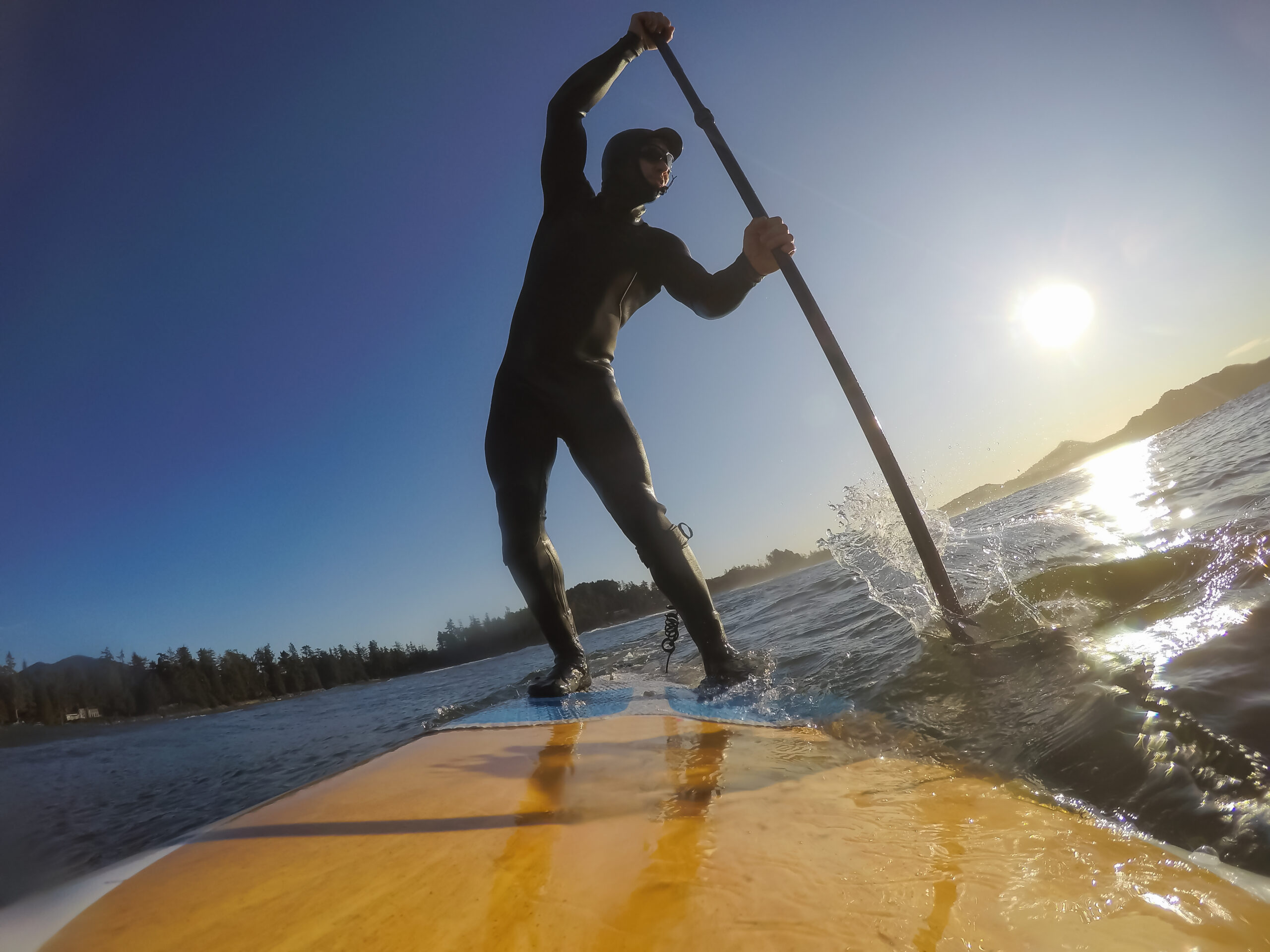 Adventurous Man Surfer on a paddle board is surfing in the ocean during a sunny morning in Fall Season. Taken in Long Beach, Tofino, Vancouver Island, BC, Canada.