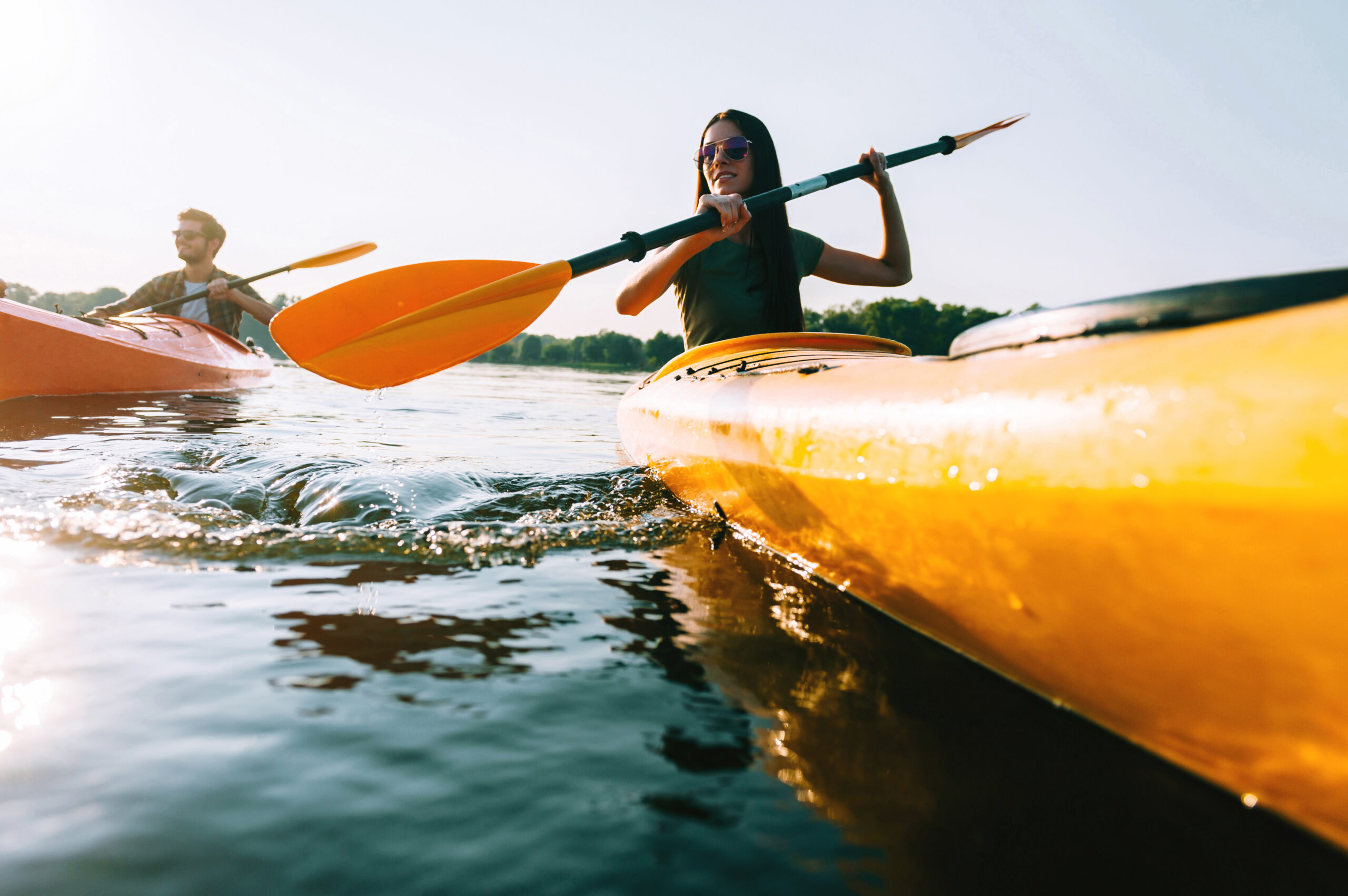 Couple kayaking. Low angle view of beautiful young couple kayaking on lake together and smiling